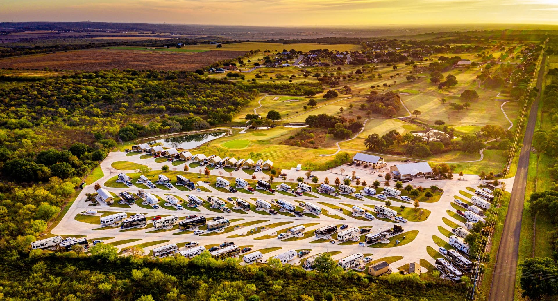 Golden-hour aerial view of Alsatian RV Resort, nestled beside the adjacent golf course